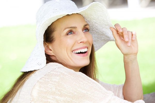 Woman smiling with a white floppy hat